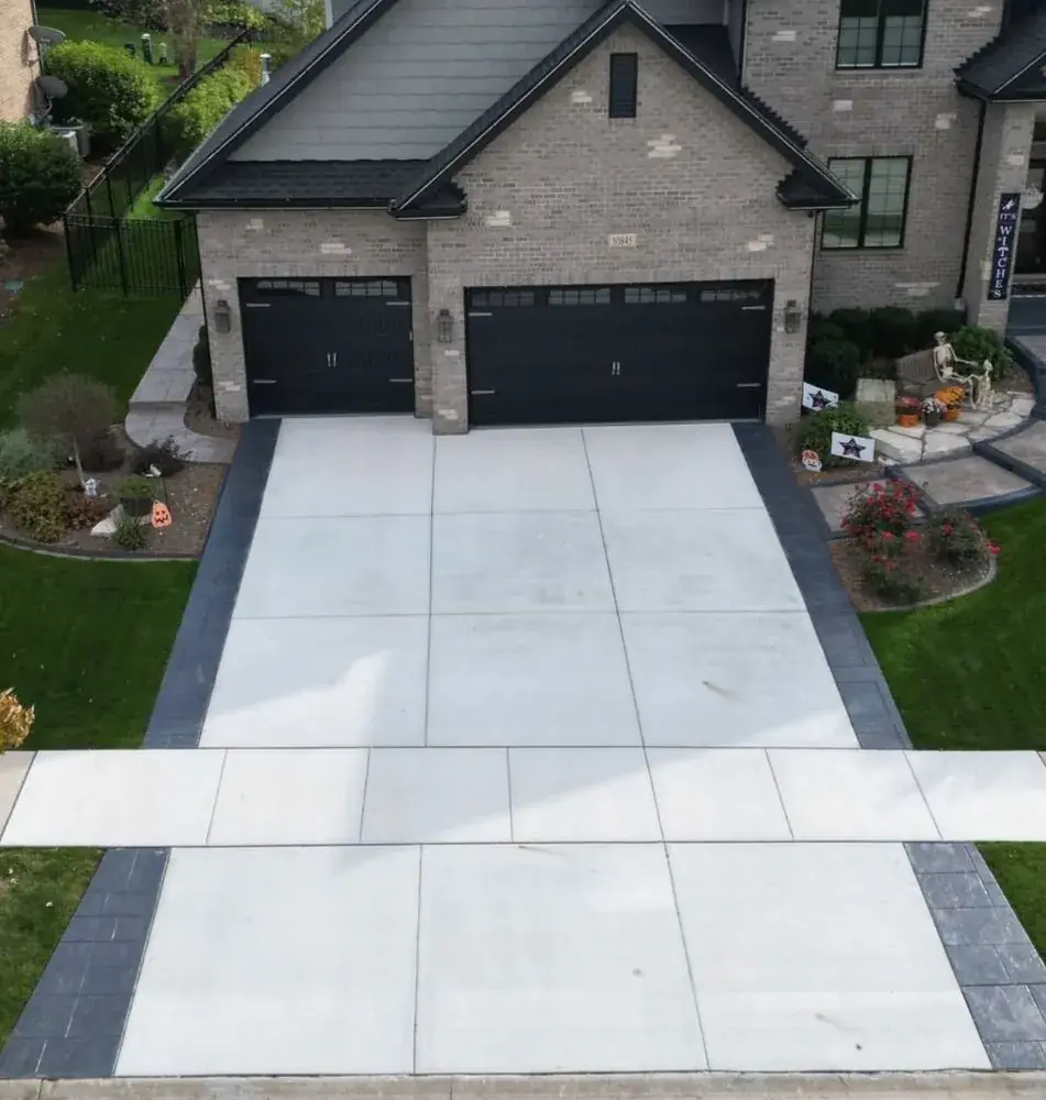 New concrete driveway with dark border bands leading to a two-car garage